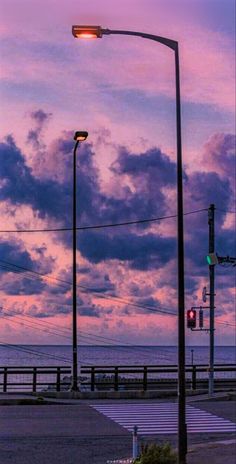 an empty parking lot next to the ocean under a purple and blue sky with clouds