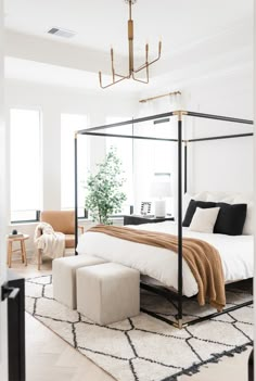 a bedroom with a four post bed, white walls and rugs on the floor