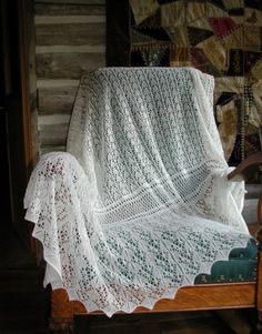 a white crocheted blanket sitting on top of a wooden chair