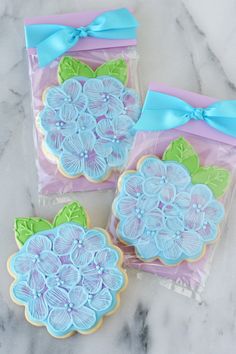 three decorated cookies sitting on top of a marble counter covered in blue and green icing