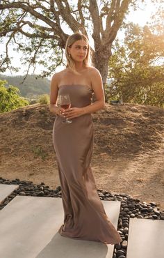 a woman in a brown dress holding a wine glass