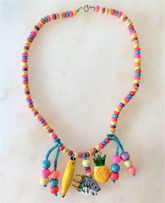 "Kids 15\" Brite Multi Colored Coco Beads Necklace with Hand Painted Wooden Charms & Beads Brite Multi Coco Chips Necklace Hand Painted Wooden Fish, Pineapple & Banana Charms Turquoise Cord with Multi Colored Wooden Beads Wooden Charms Hang Approx 1 1/2\" Long Silver Tone Spring Ring Clasp Made in the Philippines COMPLIMENTARY DOMESTIC SHIPPING" Adjustable Yellow Wooden Beads Necklace, Adjustable Yellow Necklaces With Wooden Beads, Adjustable Yellow Necklace With Wooden Beads, Traditional Multicolor Heart Beads Necklace, Colorful Adjustable Fun Beaded Necklaces, Multicolor Dangling Beads Beaded Bracelets For Beach, Beach Multicolor Beaded Bracelets With Dangling Beads, Multicolor Beaded Bracelets With Dangling Beads For Beach, Multicolor Heishi Beaded Necklaces With Large Beads