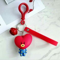 a red heart shaped keychain with a small bear on it's side