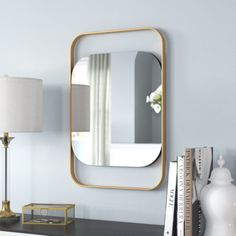 a mirror sitting on top of a wooden dresser next to a lamp and bookcase