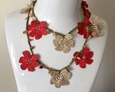 a crocheted flower necklace on a mannequin headpiece with red flowers