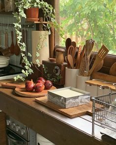 the kitchen counter is cluttered with utensils and other cooking implements, including an apple on a cutting board