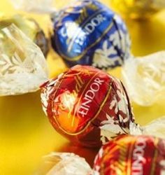 chocolate candies are lined up on a yellow tablecloth with foil wrapped around them