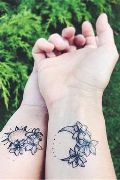 two people holding hands with tattoos on their wrist and one has a crescent moon in the middle