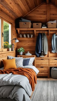 a bedroom with wooden walls and shelves filled with clothes, pillows and blankets on top of the bed