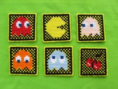 four squares with different designs on them sitting on top of a green surface, one is made out of beads and the other has eyes