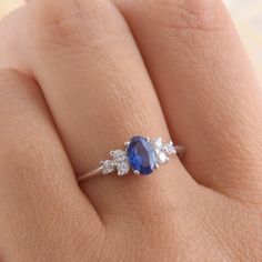 a woman's hand with a blue and white diamond ring on her left hand