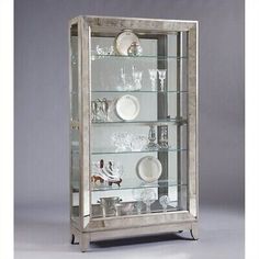 a silver and glass display case with dishes on it's sides, in front of a gray background