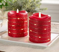 two red candles sitting on top of a white tray