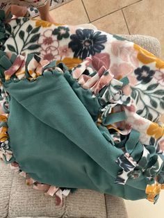 a woman sitting on top of a couch next to a flowered blanket with ruffles