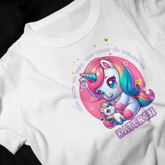 a white t - shirt with an image of a unicorn holding a stuffed animal on it's chest