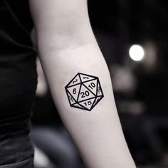 a black and white photo of a woman's arm with a dice tattoo on it