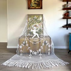 a chair with a white net covering it and a painting on the wall behind it