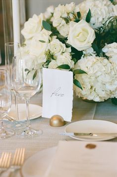 the table is set with white flowers and place cards