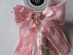 a clock with pink ribbons and bows on it's face, next to a ribbon