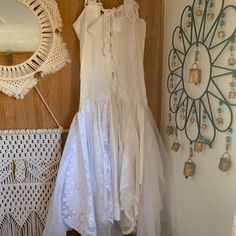 a white dress hanging up against a wall next to a mirror and doily on the wall