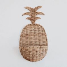 a wicker pineapple shaped wall hanging on a white wall