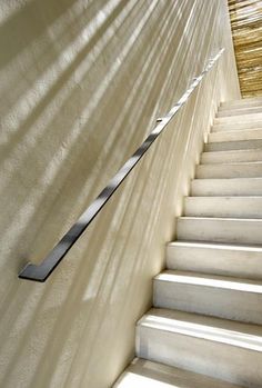 there is a long metal stair rail on the side of a wall next to some stairs