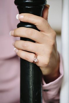 a woman's hand on top of a black pole with a diamond ring in it