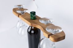 three wine glasses and a beer bottle on a wooden shelf with two empty glass holders