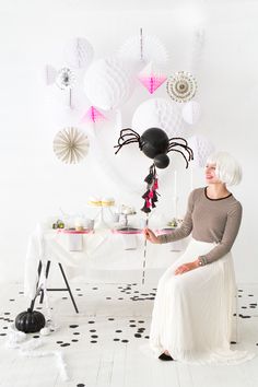 a woman with white hair sitting in front of a table filled with balloons and decorations