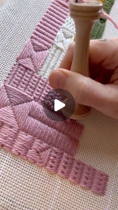 someone is stitching on a piece of fabric with a wooden needle and yarn ball