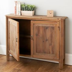 a wooden cabinet sitting on top of a hard wood floor next to a white wall