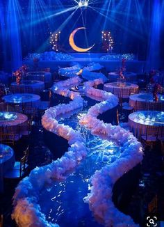 a stage set up for a party with blue lighting and white linens on the floor