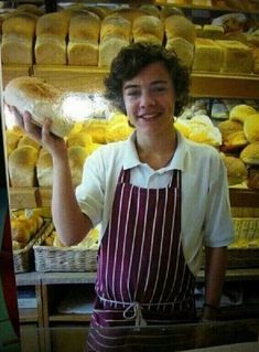 a woman in an apron holding up a loaf of bread