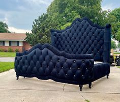 a large blue couch sitting in the middle of a sidewalk next to a house and trees