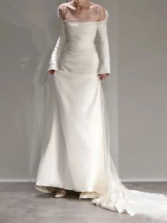 a woman in a white dress is standing on the runway with her hands behind her head