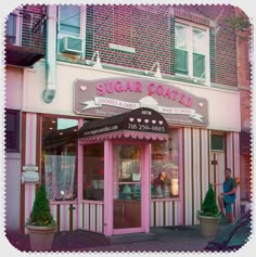 there is a pink and white building that has a sign on the front saying sugar cake