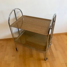 a metal and wood serving cart sitting on top of a hard wood floor