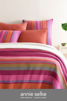 an orange and pink striped bed spread with pillows