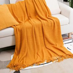 a living room with a white couch and yellow blanket