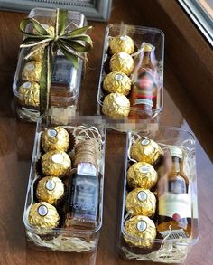 four clear boxes filled with different types of chocolates and bottles of wine sitting on a table