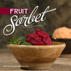 a wooden bowl filled with fruit sorbet on top of a table next to other food