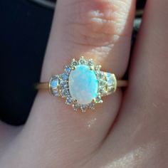 a woman's ring with an opal and diamonds on it