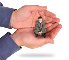 two hands holding a small figurine of a man in a suit and tie