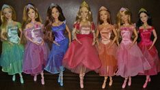 six barbie dolls lined up next to each other in dresses and tiaras, all wearing different colored gowns