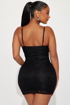 a woman in a black dress with her back turned to the camera, looking down