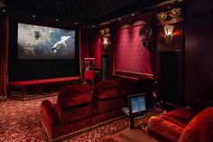 a home theater with red velvet seats and curtains, in front of a large screen