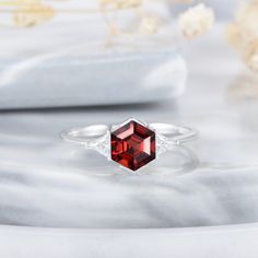 a close up of a ring with a red stone in it on a marble surface