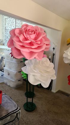 three large paper flowers sitting on top of each other in front of a wall with windows