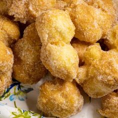 some sugared donuts are on a plate with a flower print napkin and wooden spoon