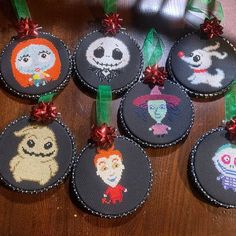 cross stitch ornament with halloween characters hanging from green ribbon on wooden table top